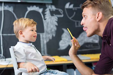 Speech therapist using various techniques to help a young patient 